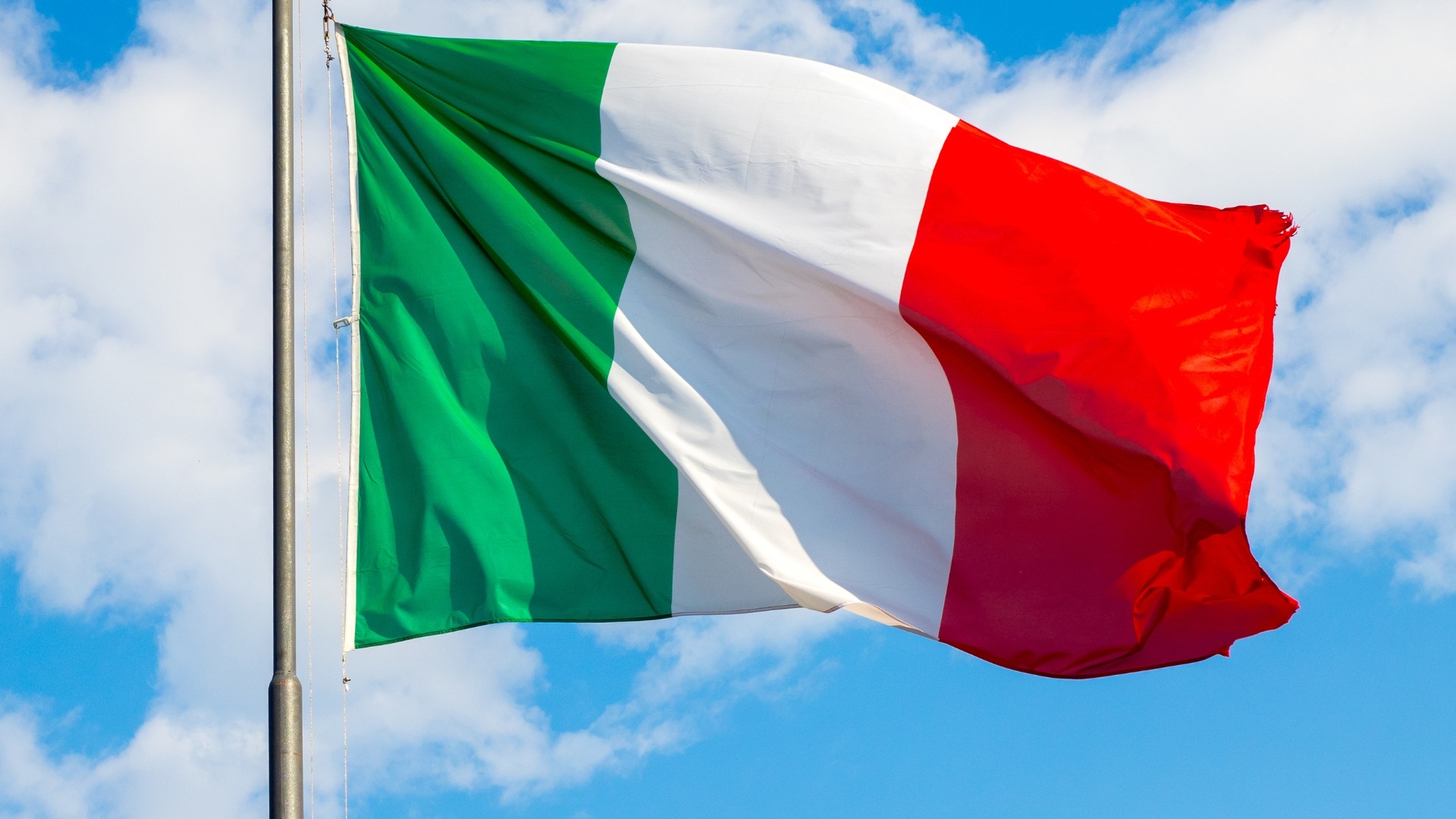 Italian flag waving against a blue sky with clouds