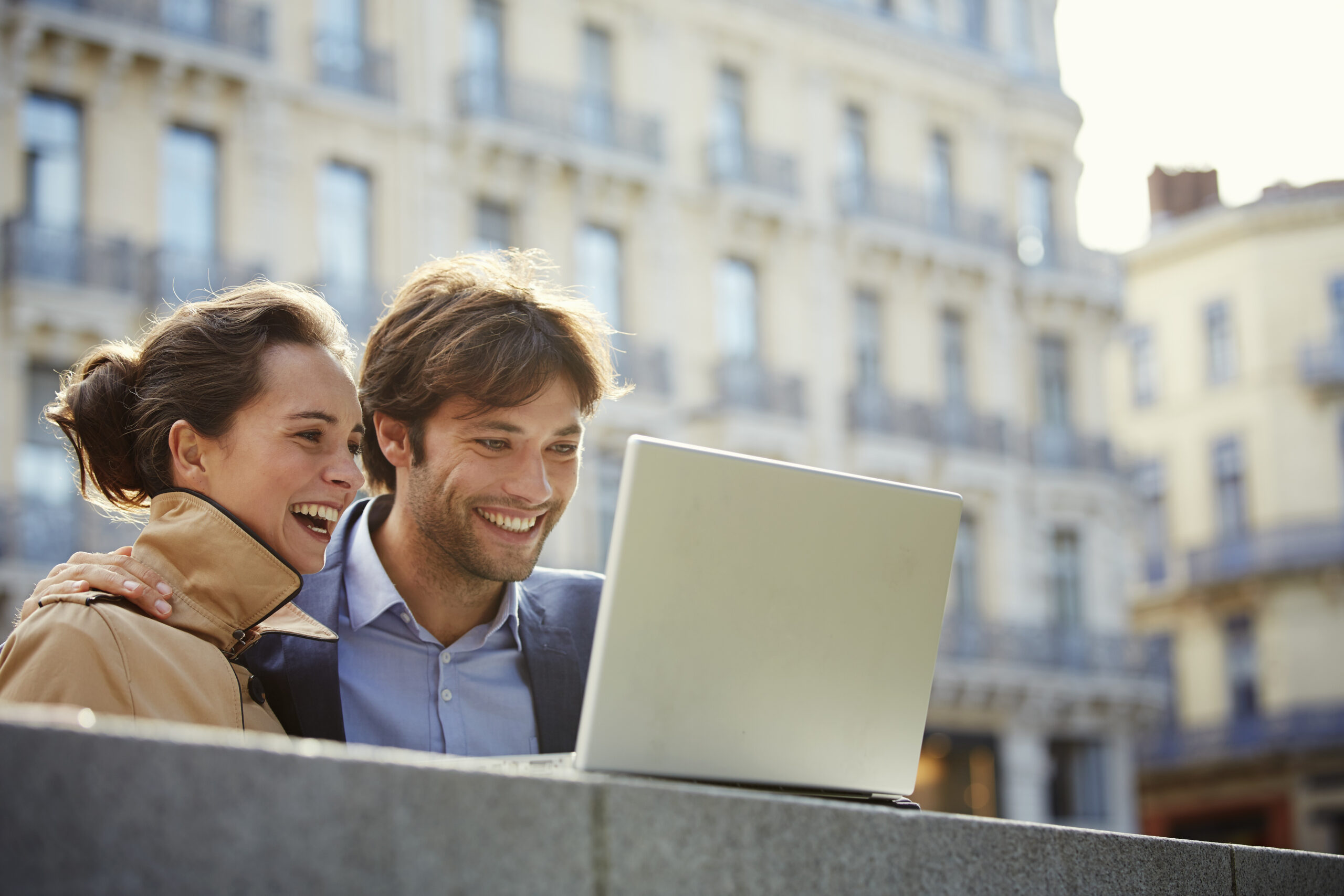Couple working remotely on a laptop while living in a European coastal city environment