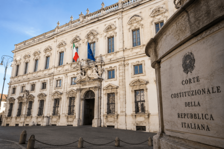 Italian Constitutional Court building in Rome with Italian and European Union flags displayed on the façade, symbolizing a key legal debate on Italian citizenship by descent and constitutional protections for applicants affected by the 2025 citizenship reform.