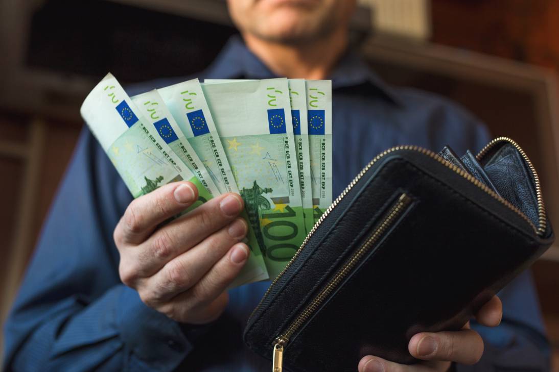 A man's hand takes money from his wallet putting money