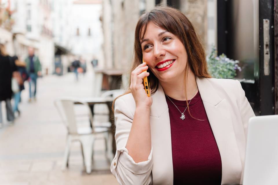 Businesswoman smiling while talking on phone in outdoor cafe