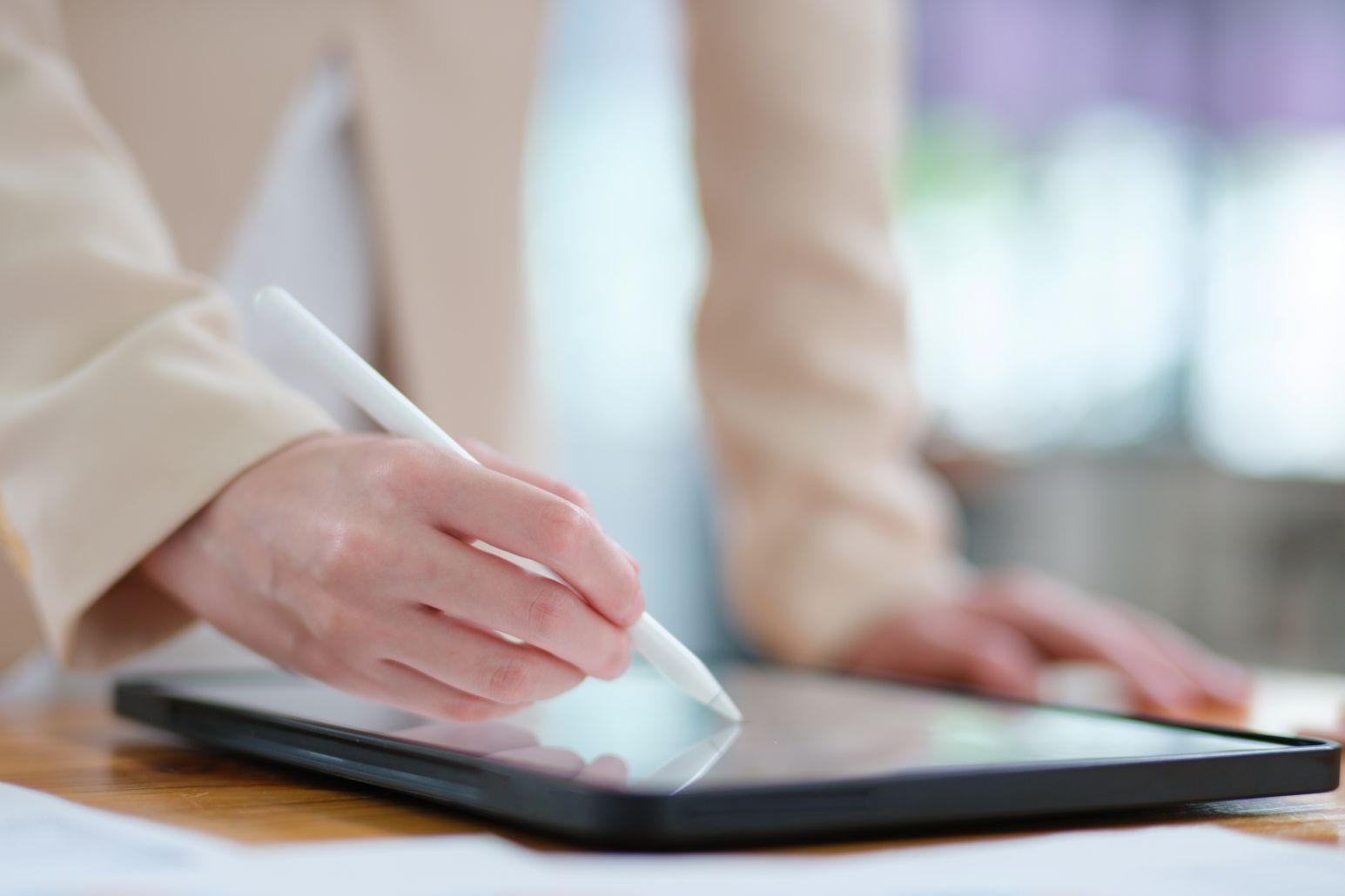 Close-up of hand signing electronic documents on a tablet with a digital pen for online workflows
