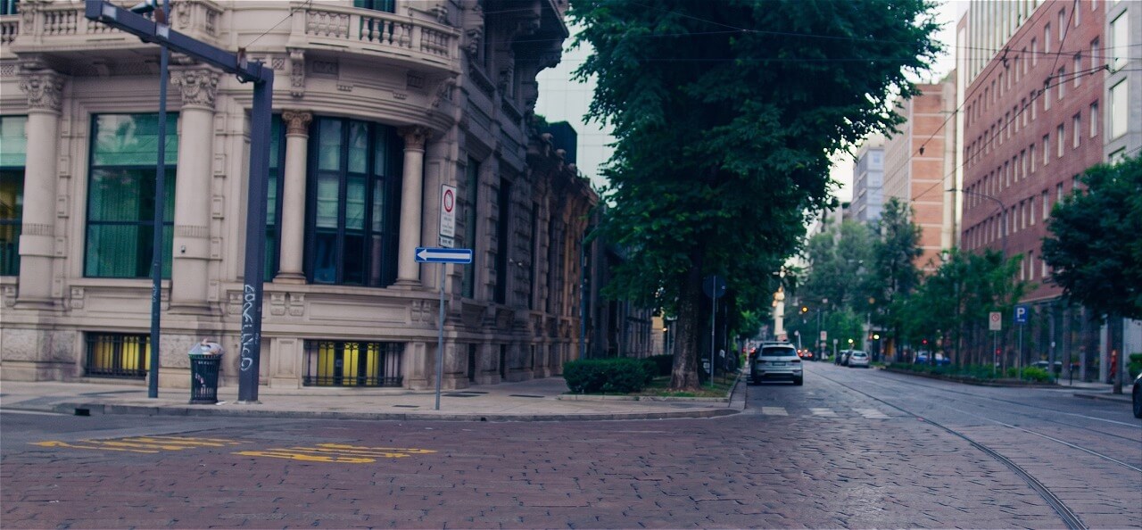 Historic Milan street corner with cobblestone paving and tram lines at dawn