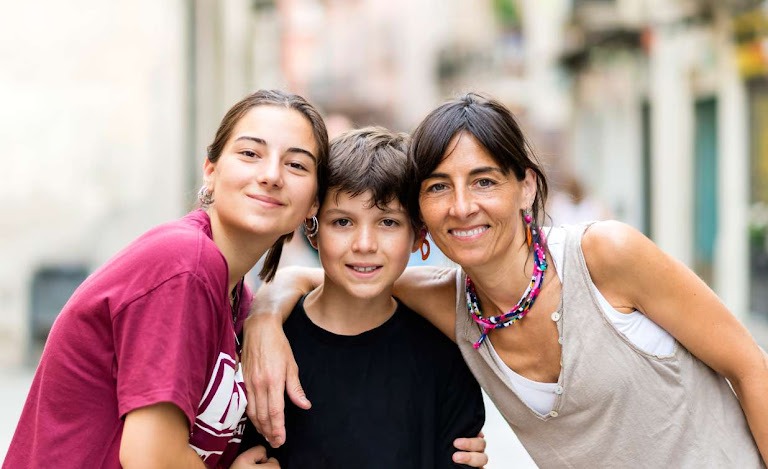 Affectionate people mom teen daughter and little son embracing outside sunny day