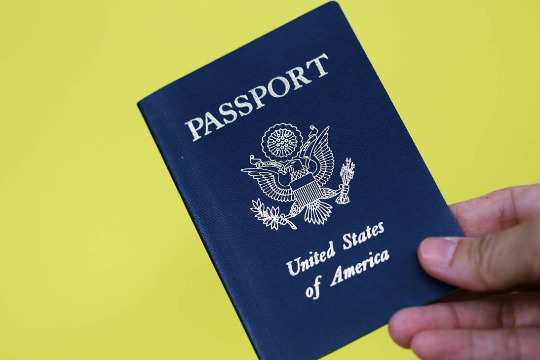 People hand holding USA passport closeup yellow texture background