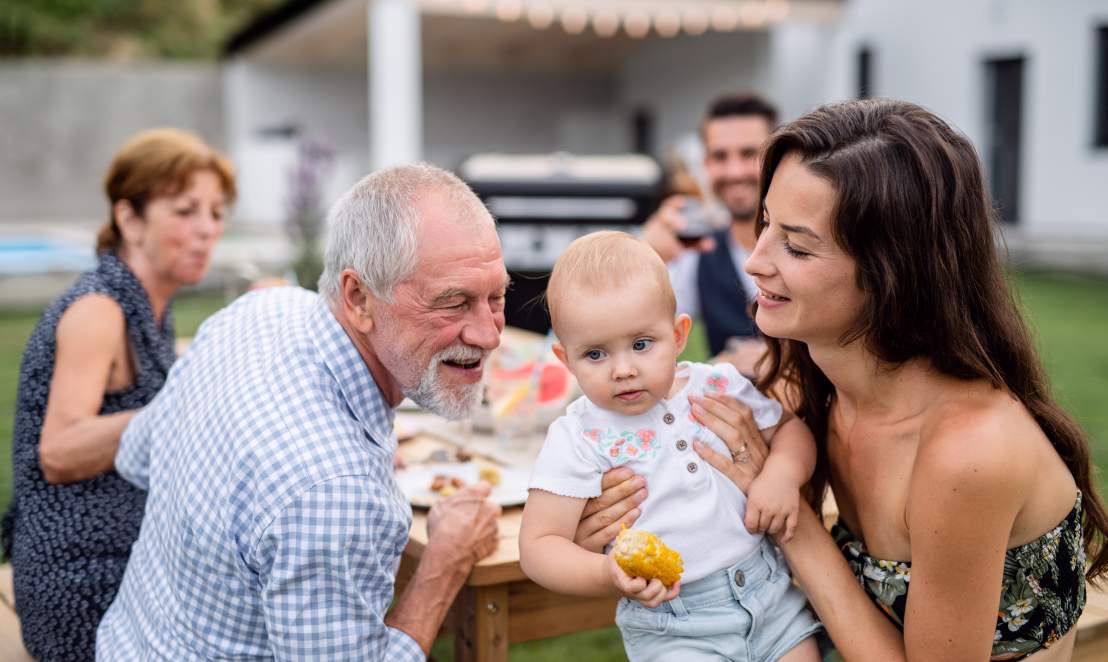 Portrait of extended family sitting at table outdoors on garden barbecue