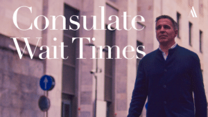 Man walking outside a building with “Consulate Wait Times” text overlay
Titolo