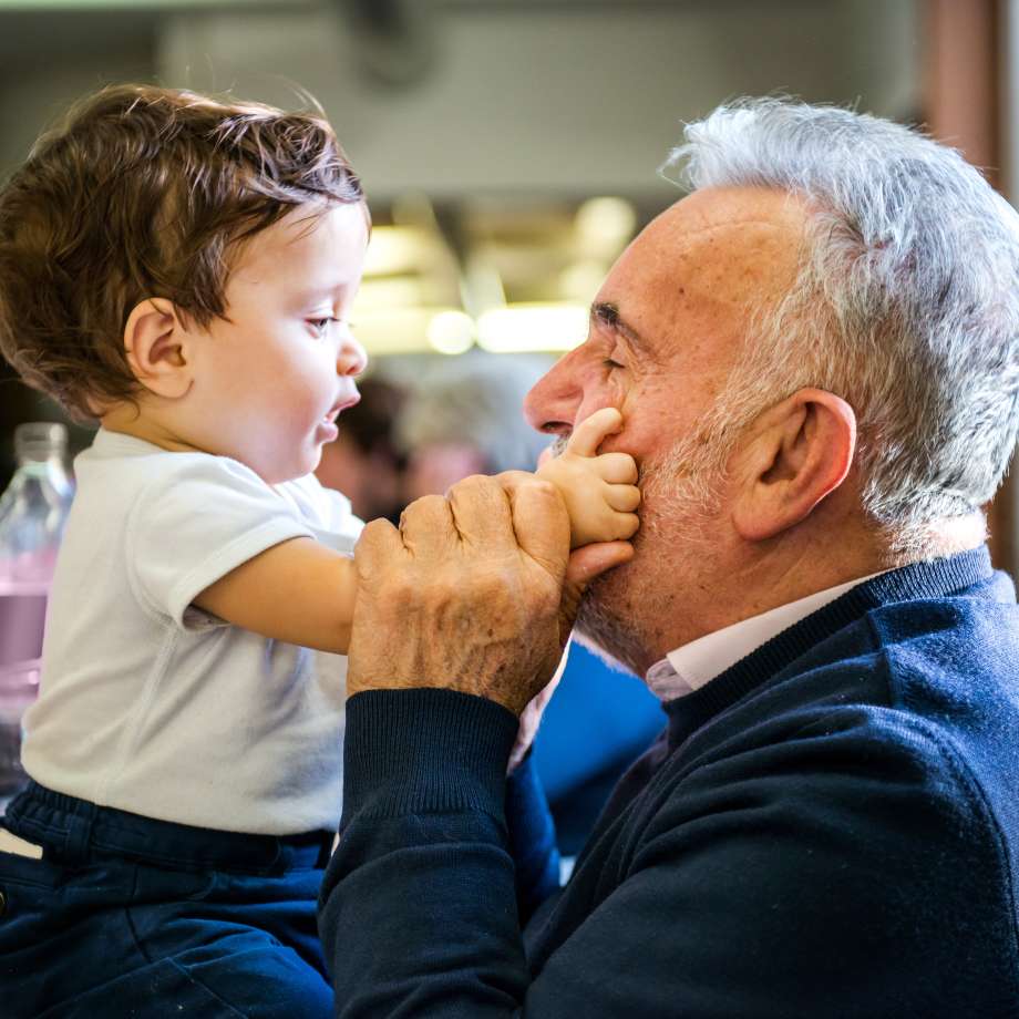 Senior man face to face with baby grandson in cafe