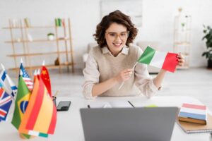 Young teacher holding flag of Italy near laptop