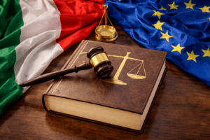 judge’s gavel, a legal book with scales of justice, and the flags of Italy and the European Union, symbolizing the legal framework surrounding jure sanguinis and the Constitutional Court’s role in evaluating recent reforms to Italian citizenship law.